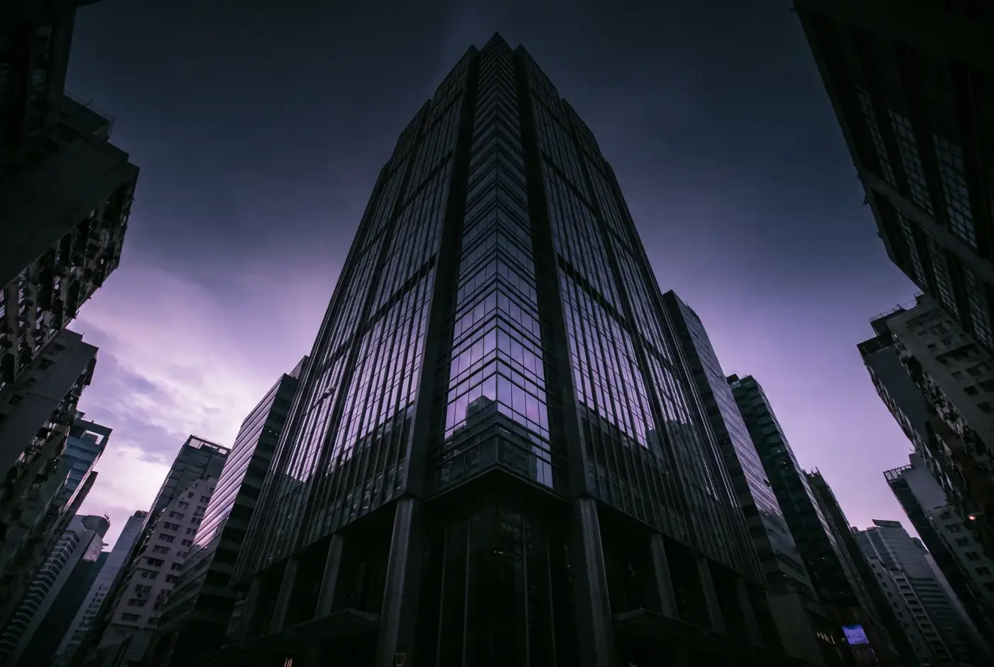Dark skyscraper facade at violet dusk in a financial district
